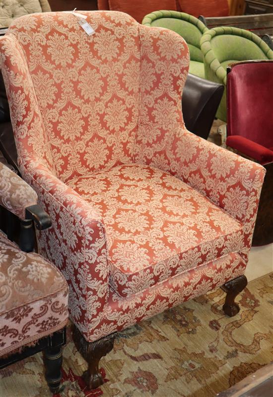 A 1920s upholstered tub framed armchair, with claw and ball feet